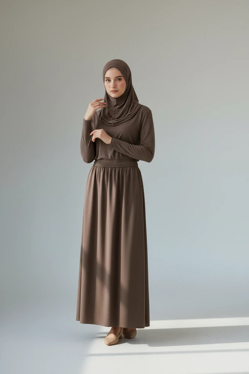 Modèle portant la jupe longue taupe Shanaluxe avec taille élastique froncée et poches latérales sur fond neutre
